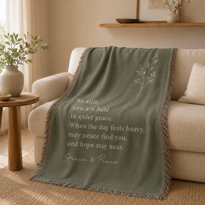 Grace and Peace sage green woven blanket draped over a cream sofa